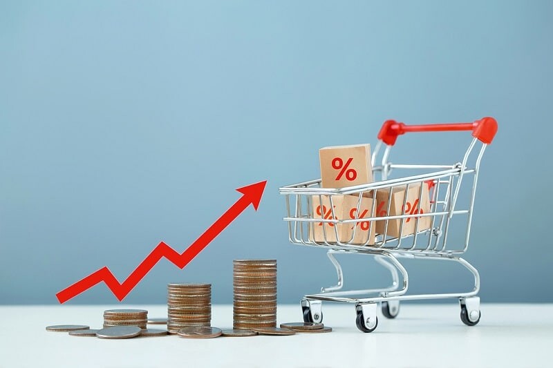 Inflation and the economic crisis. Financial market crash. The red arrow on the chart is pointing up at the stacks of coins and shopping cart. higher inflation rate compared to the product received.